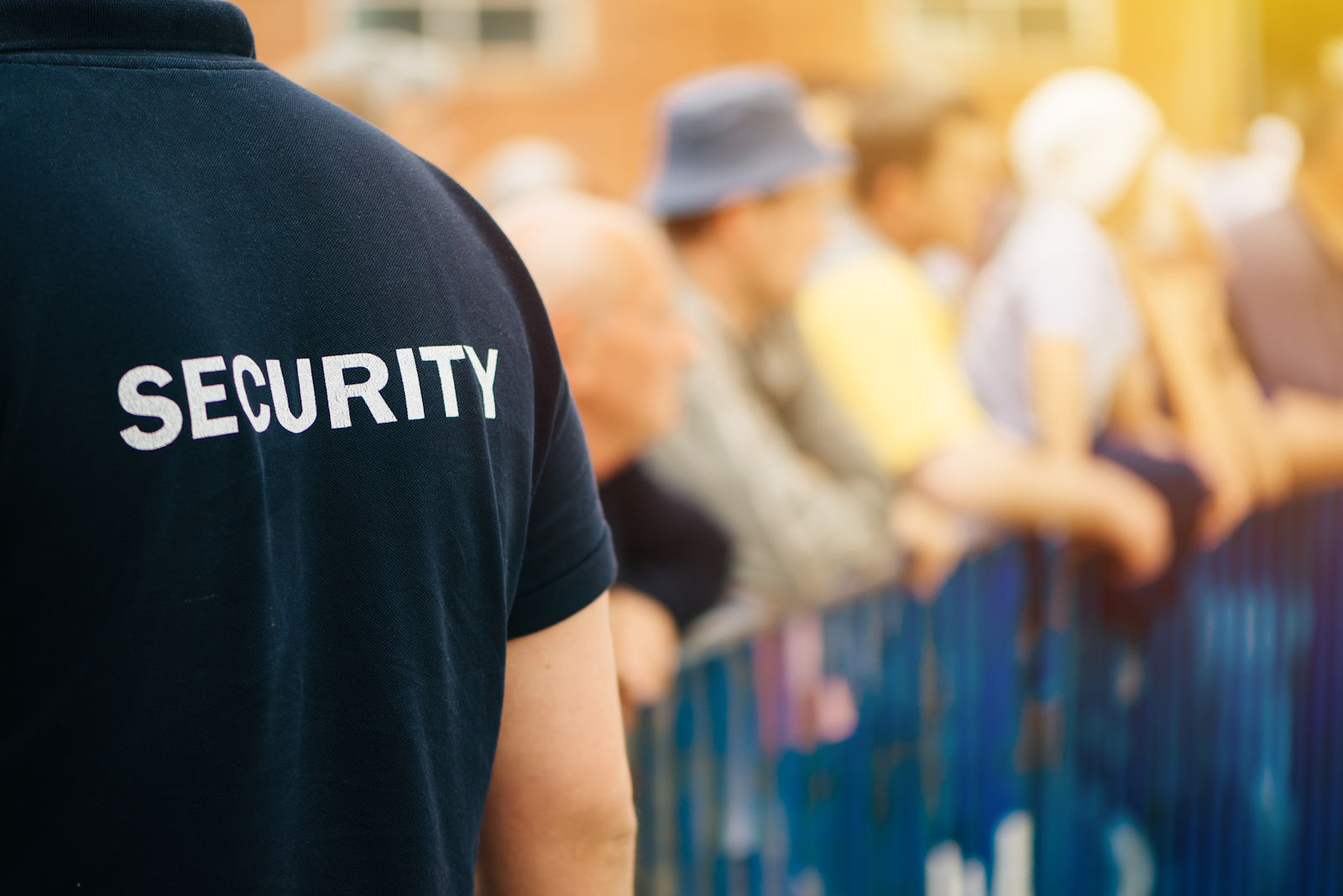 Sicherheitsmitarbeiter vor einem Absperrgitter mit Besuchern